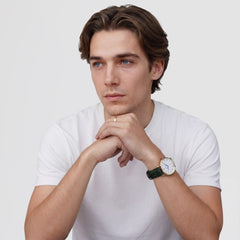 A man wearing a white T-shirt showcases the Classic Roman Numerals Date Dark Green Croc Belly Gold watch, highlighting its gold case, white dial with Roman numerals, and dark green crocodile-embossed leather strap.