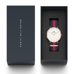 Classic Oxford Rose Gold watch with a blue and red NATO strap, presented in a sleek Daniel Wellington gift box, ideal for gifting or adding to your collection.