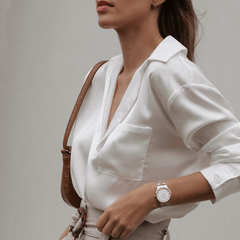 Woman wearing the Iconic Link Lumine Rose Gold watch with a two-tone rose gold and silver bracelet and eggshell white dial, styled with a crisp white blouse and neutral accessories for a polished, professional look.