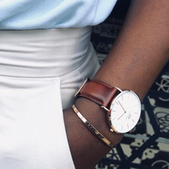 Classic St Mawes Rose Gold watch with a brown leather strap and minimalist white dial, styled on the wrist with a rose gold bangle for a polished, everyday look.