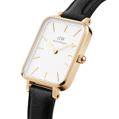 Quadro Pressed Sheffield Gold ladies watch with a rectangular gold stainless steel case, white dial, gold markers, and a slim black leather strap, shown in a close-up angled view.