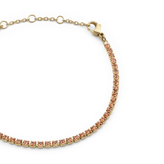 Close-up of the Classic Tennis Bracelet Apricot Gold showing apricot-coloured crystals set in gold, with adjustable sizing rings and a lobster clasp for a secure fit.