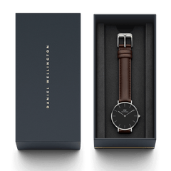 Petite Bristol Black Silver watch with a dark brown leather strap and minimalist black dial, elegantly presented in a Daniel Wellington branded gift box.