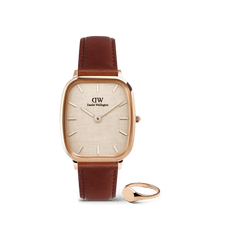 Rose gold Daniel Wellington watch with a cushion-shaped case, textured yellow dial, and brown leather strap, paired with a polished rose gold mini signet ring, both displayed against a plain background.