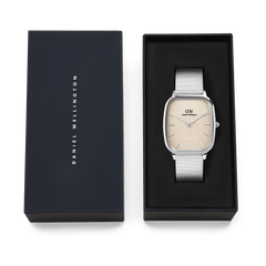 Marlon Wire Linen Silver men’s watch with a rectangular stainless steel case and silver mesh strap, presented in a black Daniel Wellington gift box with a soft yellow linen-textured dial.