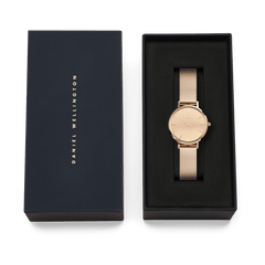 Petite Reflection Rose Gold watch by Daniel Wellington displayed in an elegant black gift box, featuring a slim rose gold mesh strap and minimalist mirror-effect dial.