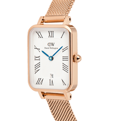 Quadro Melrose Roman Numerals Date watch featuring a rose gold rectangular case, white dial with Roman numerals, blue hands, and a rose gold mesh strap, shown in close-up to highlight its elegant details.