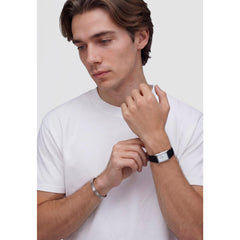 A person wearing the Bound Black Crocodile Guilloché Silver watch, showing its rectangular silver case, white textured dial, and black crocodile-embossed leather strap styled with a casual white T-shirt.