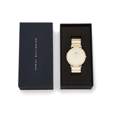 Classic Piano Link Gold Unitone watch with a brushed gold dial and piano link bracelet, presented in a black Daniel Wellington gift box.