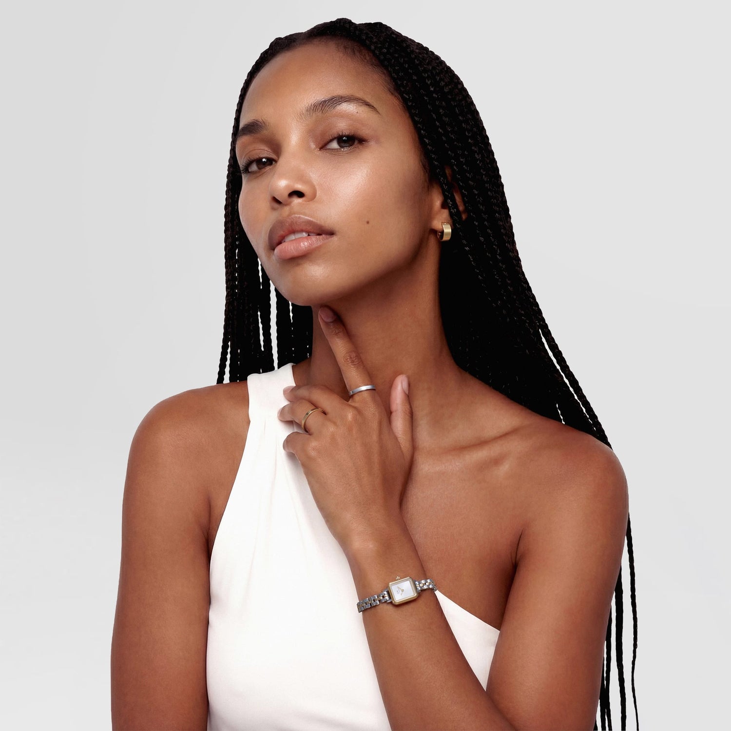 A woman wearing the Quadro Mini Arch 3-Link Two Tone Gold watch on her wrist, styled with a white sleeveless top, highlighting the slim gold and silver bracelet and minimalist rectangular case for a modern, elegant look.