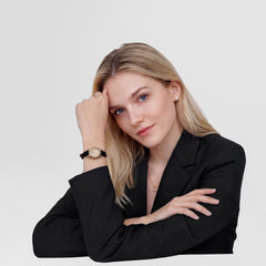 A woman wearing the Daniel Wellington Ophelia Mini Black Lizard Unitone Guilloché Gold watch, styled with a black blazer, showcasing the petite gold oval case and black lizard-textured leather strap for a refined, everyday look.