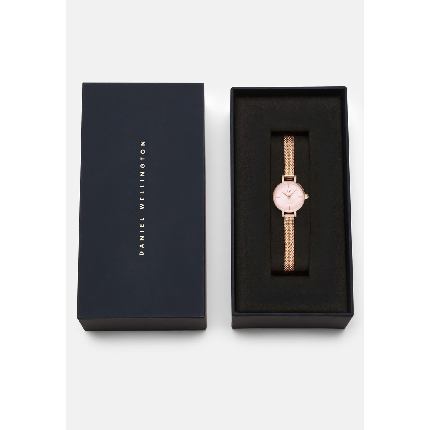 Petite Mini Blush Melrose watch with a blush pink dial and rose gold mesh strap, presented in a sleek black Daniel Wellington gift box, ideal for gifting or adding to your collection.