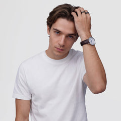 A man wearing a white t-shirt showcases the Classic Roman Numerals Date Dark Brown Croc Belly Silver watch on his wrist, highlighting the elegant silver case, white dial with Roman numerals, and dark brown crocodile-embossed leather strap in a casual setting.