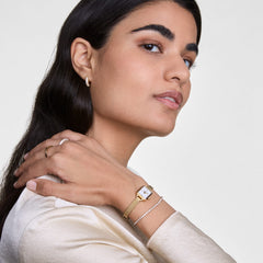 Classic Tennis Bracelet Gold worn on the wrist, styled with a gold watch and matching jewellery, showcasing its slim profile and sparkling cubic zirconia stones for an elegant everyday look.