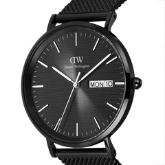 Close-up of the Classic Day Display Onyx Black watch showing its textured black dial, minimalist hour markers, and clear day and date display, paired with a black mesh stainless steel strap.