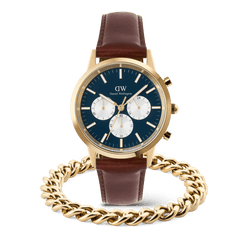 Iconic Chronograph Panda watch by Daniel Wellington with a blue dial, gold case, and brown leather strap, paired with an Ellipse Cuban Chain Bracelet in polished gold.