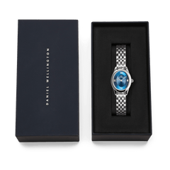 Ophelia Mini Arctic Silver ladies watch with a polished silver oval case, blue sunray dial, and slim 5-link bracelet, presented in a Daniel Wellington branded gift box.