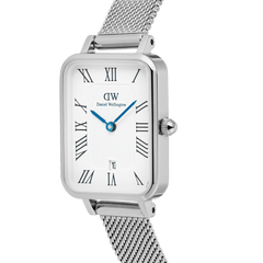 Close-up of the Quadro Sterling Roman Numerals Date ladies watch, showing the rectangular polished stainless steel case, white dial with Roman numerals, blue hands, date window, and textured silver mesh strap.