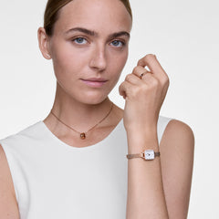 Woman wearing the Elan Necklace Rose Gold with a minimalist ring pendant, styled with a matching rose gold watch and ring, complementing a sleeveless white top for a modern, elegant look.