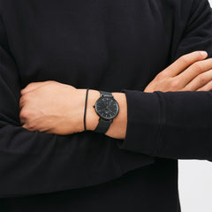Classic Multi-Eye Ashfield Onyx men's watch with a black mesh strap and minimalist black dial, worn on the wrist with a black long-sleeve top for a sleek, modern look.