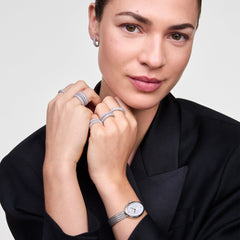 A woman wearing the Juliette Braided Mesh White Sunray Silver ladies watch, featuring a slim braided stainless steel strap and oval white sunray dial, styled with silver jewellery and a black blazer for a modern, elegant look.