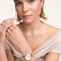 A woman wears the Crystal Zodiac Chain Necklace Silver with a Libra zodiac pendant, styled with a gold watch, matching zodiac bracelet, and elegant rings for a refined, layered jewellery look.