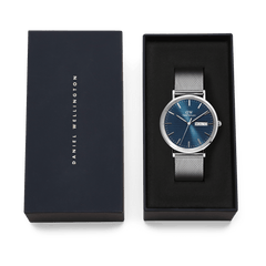 Classic Day Display Sterling Arctic men's watch with a blue patterned dial and stainless steel mesh strap, presented in a Daniel Wellington branded gift box.