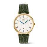 Gold men’s watch with a white dial, Roman numerals, blue hands, and a date window, featuring a dark green crocodile-embossed leather strap.