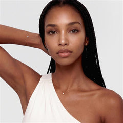 Mirelle Solitaire Stud Earring Gold worn in a minimalist style, featuring a petite cubic zirconia crystal in a gold setting, paired with a delicate gold necklace and bracelet for an elegant everyday look.