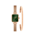 Quadro Mini Melrose Emerald watch with a rectangular emerald green dial and rose gold mesh strap, paired with a minimalist rose gold Classic Bracelet engraved with Daniel Wellington branding.