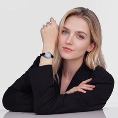 A woman wearing the Daniel Wellington Ophelia Mini Black Lizard Ice Blue Guilloché Silver watch, styled with a black lizard-embossed leather strap and an elegant ice blue oval dial, paired with a black blazer for a refined, modern look.