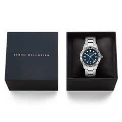 Daniel Wellington Iconic GMT Link Brushed Bezel Silver watch with a blue dial and stainless steel bracelet, elegantly presented in its branded gift box.