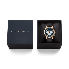 Iconic Chronograph Sheffield Arctic Panda Rose Gold watch with a deep blue dial, white sub-dials, and black leather strap, presented in a branded Daniel Wellington gift box.
