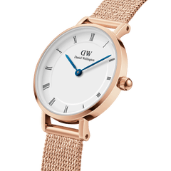 Close-up of the Petite Roman Numerals Melrose ladies watch featuring a rose gold mesh strap, minimalist white dial with Roman numerals, and blue steel hands.
