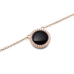 Close-up of the Audrey Necklace Black Agathe Rose Gold pendant, showcasing a domed black agate stone surrounded by a halo of sparkling white cubic zirconia crystals on a delicate rose gold chain.
