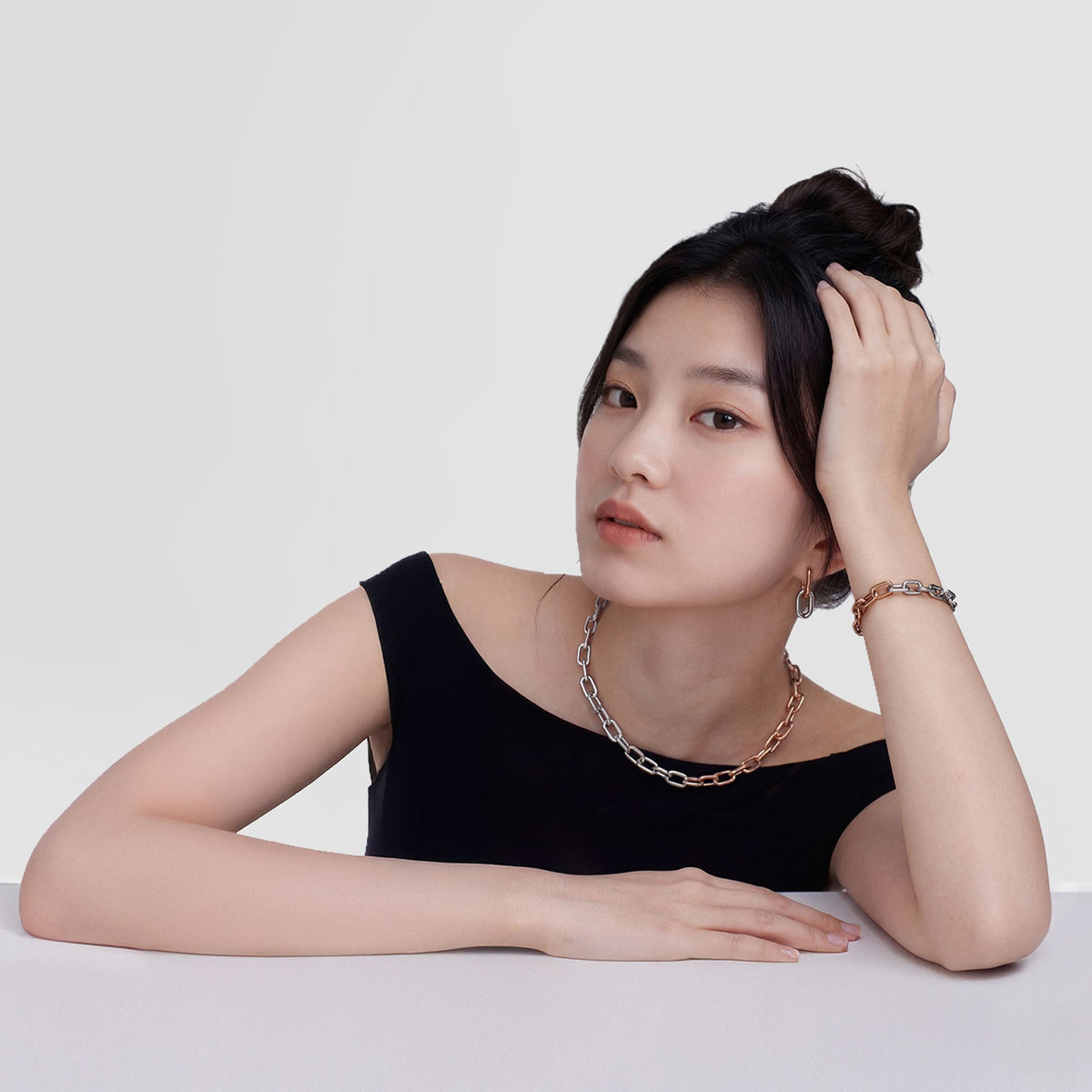 A woman wearing the Contrast Link Earrings Two Tone Rose Gold, styled with a matching two-tone chain necklace and bracelet, paired with a black off-shoulder top for a modern, minimalist look.