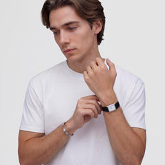 Line Cuff Brushed Silver worn on the wrist, showing its slim brushed stainless steel design paired with a white t-shirt and a classic watch for a modern, minimalist look.