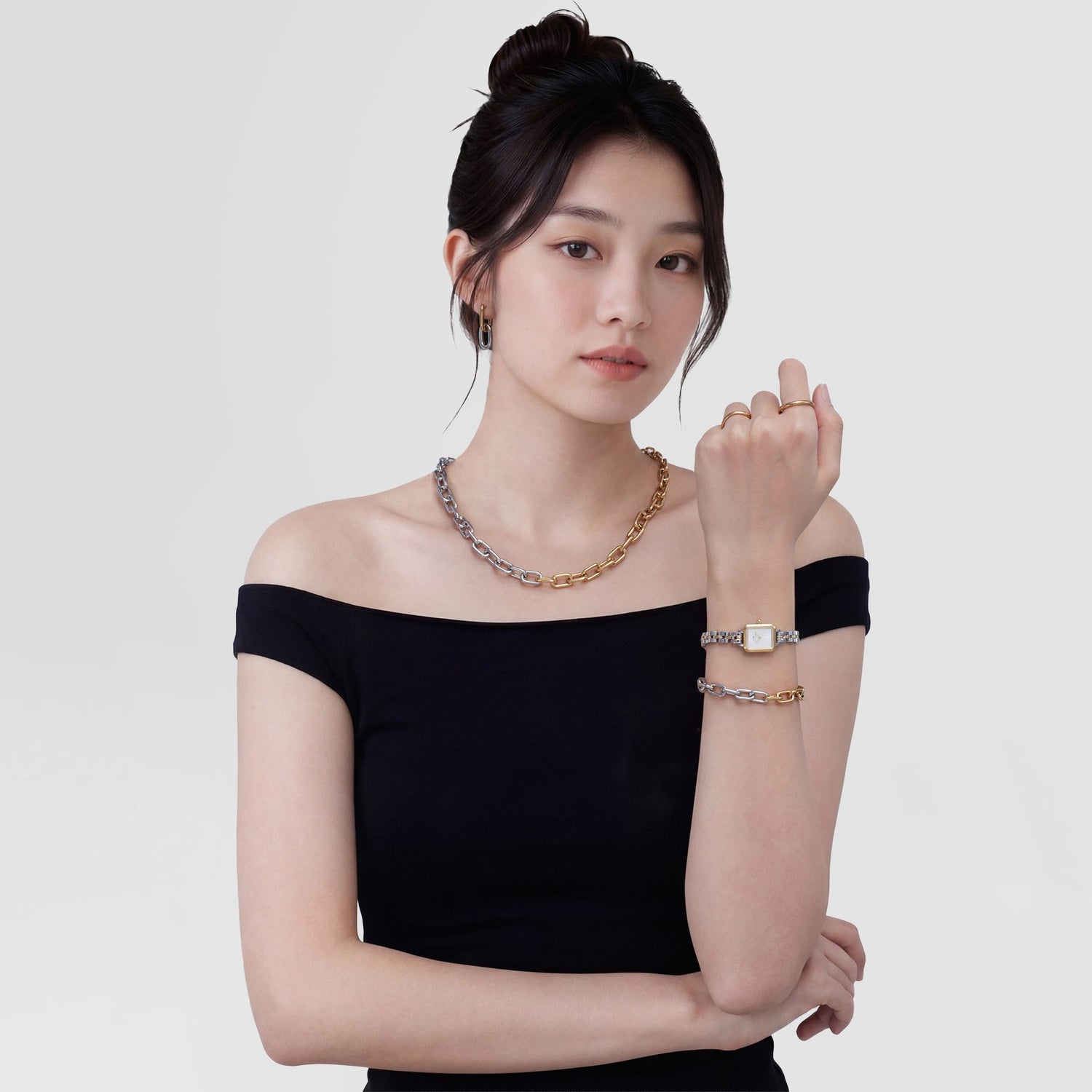 A woman wearing the Contrast Link Necklace Two Tone Gold styled with a matching two-tone bracelet and watch, paired with an off-the-shoulder black top for a modern, elegant look.