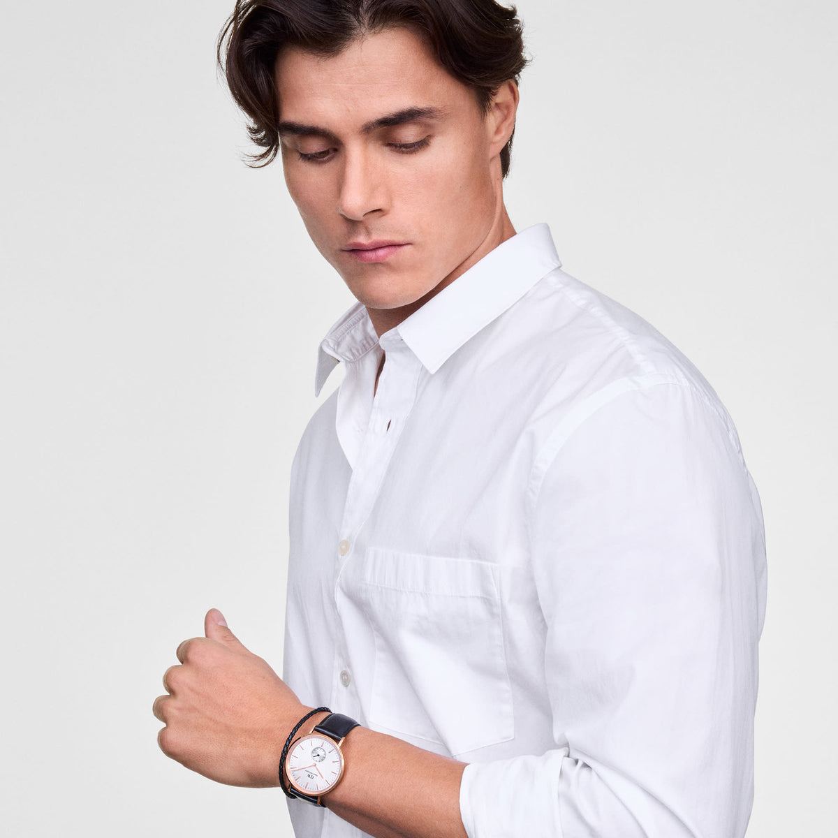 A man wearing the Classic Multi-Eye Sheffield Off-white Sunray Rose Gold watch, featuring a rose gold case, off-white sunray dial, and black leather strap, styled with a crisp white shirt for a smart, everyday look.