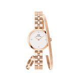 Rose gold Daniel Wellington watch with a white dial and crystal hour markers, paired with a matching rose gold bracelet and ring, both featuring delicate crystal accents for a coordinated, elegant jewellery set.
