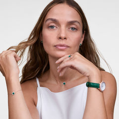 Woman wearing the Crystalline Bezel Green Croc Rose Gold ladies watch with a green crocodile-embossed leather strap and crystal-set bezel, styled with matching green jewellery and a white sleeveless top.