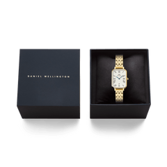 Quadro Roman Numerals Date 5-link Gold ladies watch presented in a black Daniel Wellington gift box, featuring a rectangular gold bracelet and white dial with Roman numerals.