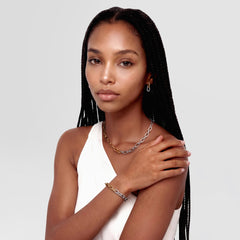 A woman wearing the Contrast Link Earrings Two Tone Gold, styled with a matching two-tone gold and silver chain necklace and bracelet, paired with a white sleeveless top for a modern, coordinated look.