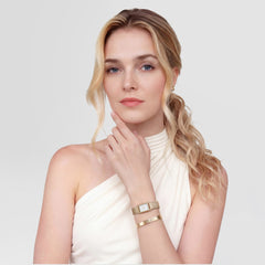 A woman wearing the Bound Mini Evergold gold watch with a rectangular white dial and gold mesh strap, styled with a matching gold bracelet for an elegant, modern look against a light background.