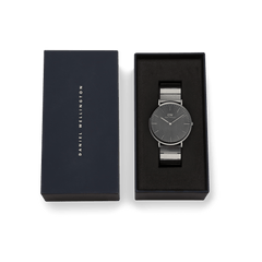 Classic Piano Link Graphite Unitone men's watch presented in its original Daniel Wellington gift box, featuring a brushed graphite dial and a matte stainless steel piano link bracelet.