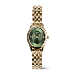 A petite gold women’s watch with an oval case, emerald green sunray dial, gold Roman numerals, and a polished gold beans link bracelet.