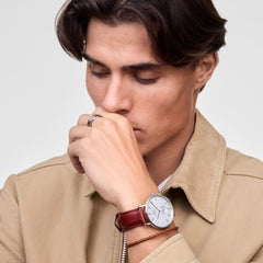 A man wearing the Daniel Braided Leather Bracelet St Mawes 2.8 Silver in tan, styled alongside a classic leather-strap watch and a beige jacket for a smart-casual look.