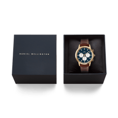 Iconic Chronograph St Mawes Arctic Panda Gold watch with a gold case, blue panda dial, and brown leather strap, elegantly presented in a black Daniel Wellington gift box.