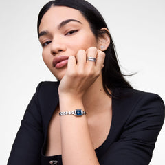 A woman wearing the Quadro Mini Arch 3-link Arctic Sunray Silver watch with a polished silver bracelet and minimalist blue dial, styled with a black outfit for a modern and elegant look.