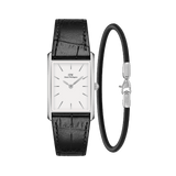 Rectangular silver Daniel Wellington watch with a white dial and black crocodile-embossed leather strap, paired with a slim Sheffield Bracelet in silver and black, both displayed against a plain background.